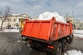 Tractor loader machine uploading dirty snow into dump truck. Cleaning city street, removing snow and ice after heavy Royalty Free Stock Photo