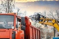 Tractor loader machine uploading dirty snow into dump truck. Cleaning city street, removing snow and ice after heavy Royalty Free Stock Photo