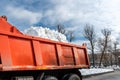 Tractor loader machine uploading dirty snow into dump truck. Cleaning city street, removing snow and ice after heavy Royalty Free Stock Photo