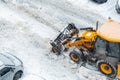 Tractor loader machine uploading dirty snow into dump truck. Cleaning city street, removing snow and ice after heavy Royalty Free Stock Photo