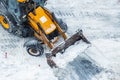 Tractor loader machine uploading dirty snow into dump truck. Cleaning city street, removing snow and ice after heavy Royalty Free Stock Photo