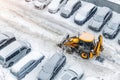 Tractor loader machine uploading dirty snow into dump truck. Cleaning city street, removing snow and ice after heavy Royalty Free Stock Photo