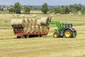 Tractor loading round bales of hay on trailer for transport to destination in the Tuscan countryside, Italy Royalty Free Stock Photo