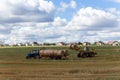 A tractor loading round hay bales on to a trailer