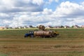 A tractor loading round hay bales on to a trailer