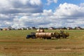 A tractor loading round hay bales on to a trailer