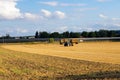 Tractor loading straw onto a trailer, on a harvested field Royalty Free Stock Photo