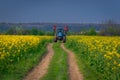 Tractor machine used in agriculture on a dirt road between two canola cozla fields Royalty Free Stock Photo