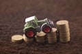 Tractor miniature with coins on fertile soil land