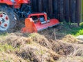 A tractor with a mower attached mulches dry grass along the fence. Land plot processing Royalty Free Stock Photo