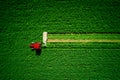 Tractor mowing green agriculture field, aerial drone view