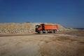 An orange dump truck, lorry full of stones in a sand quarry, transporting of materials on a natural background. Royalty Free Stock Photo