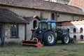 Tractor parked in the courtyard of an old farmhouse with its old stone buildings