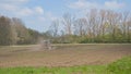 Tractor ploughing farmland in the flemish countryisde