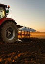 Tractor plowing field the land at sunset Royalty Free Stock Photo