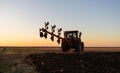 Tractor plowing field the land at sunset Royalty Free Stock Photo