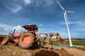 Tractor plowing in plantation farm with wind turbines clean energy electricity.