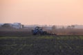 Tractor plowing plow the field on a background sunset