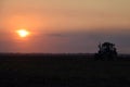 Tractor plowing plow the field on a background sunset. tractor silhouette on sunset background