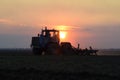 Tractor plowing plow the field on a background sunset. tractor silhouette on sunset background