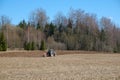 Tractor plows the earth near the forest