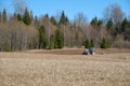 Tractor plows the earth near the forest