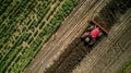 A tractor plows through a field spreading a layer of dark crumbly biochar on top of the soil. This byproduct of