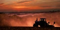 Tractor preparing land at sunset.