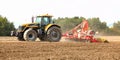 Tractor pulling ploughing / sowing trailer over dry field Royalty Free Stock Photo