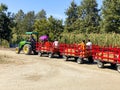 A tractor pulling a train of wagons on a seasonal adventures pumpkin patch festival.