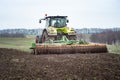 A tractor pulls a disc harrow system implement to smooth over a Royalty Free Stock Photo