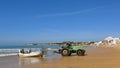 Tractor pulls a fishing boat out of the water at low tide. On the long, wide, fine sandy fisherman beach of Armacao de Pera, Silve