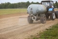 Tractor rides on the road and sprinkles the dust with water before horse races