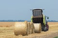 Tractor and round baler discharges. Straw Bales.
