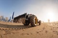 Tractor on the sandy beach cleaning, after winter, preparation for the holiday season in Italy. Wooden trunks in on the Royalty Free Stock Photo