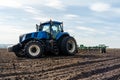 A tractor with seedbed cultivator ploughs field on morning