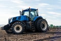 A tractor with seedbed cultivator ploughs field on morning