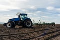 A tractor with seedbed cultivator ploughs field on morning