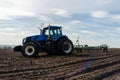 A tractor with seedbed cultivator ploughs field on morning