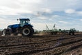 A tractor with seedbed cultivator ploughs field on morning