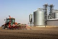 Tractor and seeder for sowing cornin. Silo in background