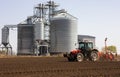 Tractor and seeder for sowing cornin. Silo in background