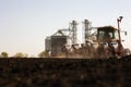 Tractor and seeder for sowing cornin. Silo in background