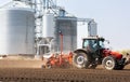 Tractor and seeder for sowing cornin. Silo in background