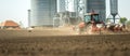 Tractor and seeder for sowing cornin. Silo in background