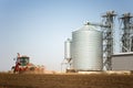 Tractor and seeder for sowing cornin. Silo in background