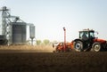 Tractor and seeder for sowing cornin. Silo in background