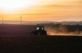 Tractor silhouette in the field on the orange-yellow sunset