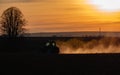 Tractor silhouette in the field on the orange-yellow sunset