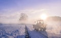 Tractor silhouette through fog, on snowy field